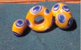 drei gelbe Schichtaugenperlen, Auen in weiß-blau-weiß-blau, bis zu 2cm Durchmesser, Lochdurchmesser bis 0,5cm