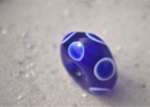 blau transluzende Perle mit weiß blauen Augen, dreimal eines mittig abwechselnd mit je zwei Schichtaugen nebeneinander