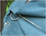 Foto eines Umhangs mit einer kleinen hufeisenförmigen Fibel und einer Ringnadel