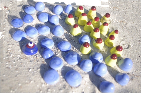 12 gelbe kegelförmige Spielsteine mit rotem Hut und 24 hell-himmblue halp-sphärische und spitzkegelige Spielsteine