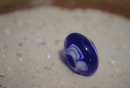 keine 2cm Durchmesser, blau transluzend, schmal, spitzkonisch beidseiter spiralig weiße gefiederte Fadenauflage