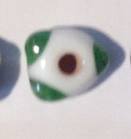 eine weiße dreieckige Perle mit grünen Tupfen auf den Spitzen