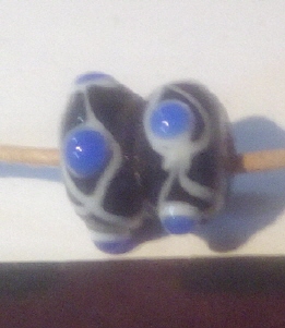 schwarze doppelte Perle, je vier weiß-blaue Schichtaugen und weiße Achterschleife