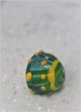 grasluzend grüne konische Perle, am schmalen Ende ein gelber Ring, 12fach gerippt, auf jeder Rippe zwei gelbe Nuppen